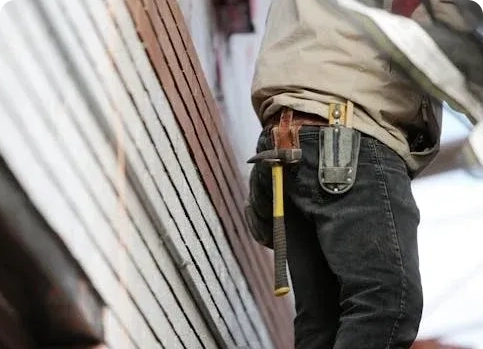 A man holding a hammer and wearing jeans.